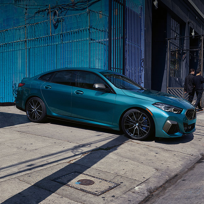 A blue metallic BMW 2 Series Gran Coupe pulling out of alley.