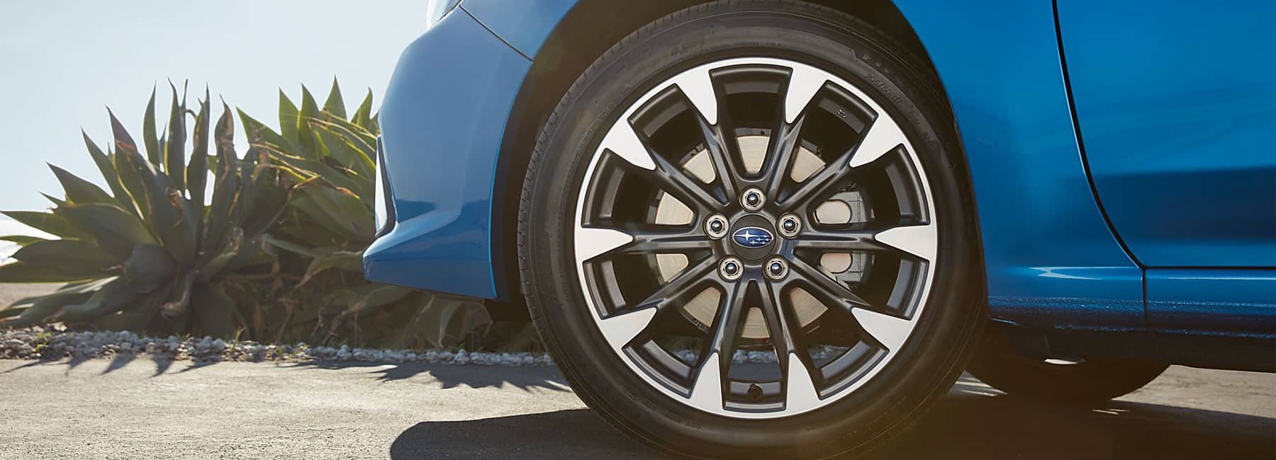  2022 Subaru Impreza- closeup front wheel-yard plants-blue