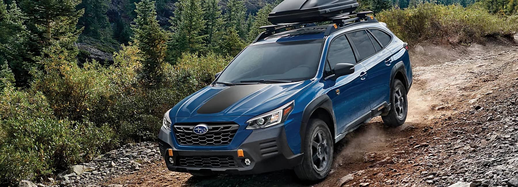 Blue 2022 Subaru Outback- driving down rocky forest trail