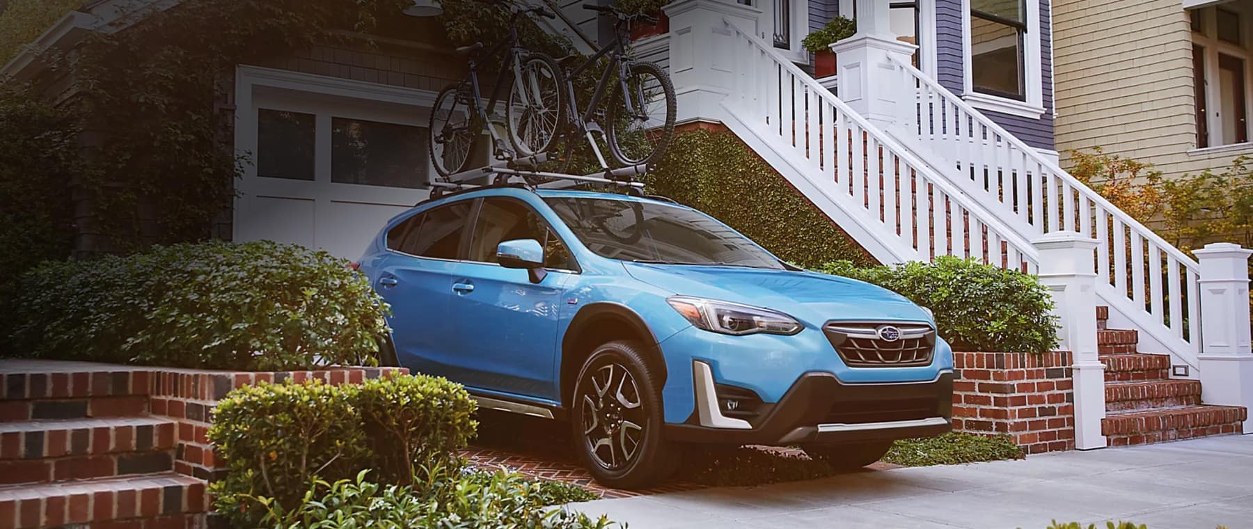 Blue Subaru Crosstrek parked in a driveway with bikes on the roof rack