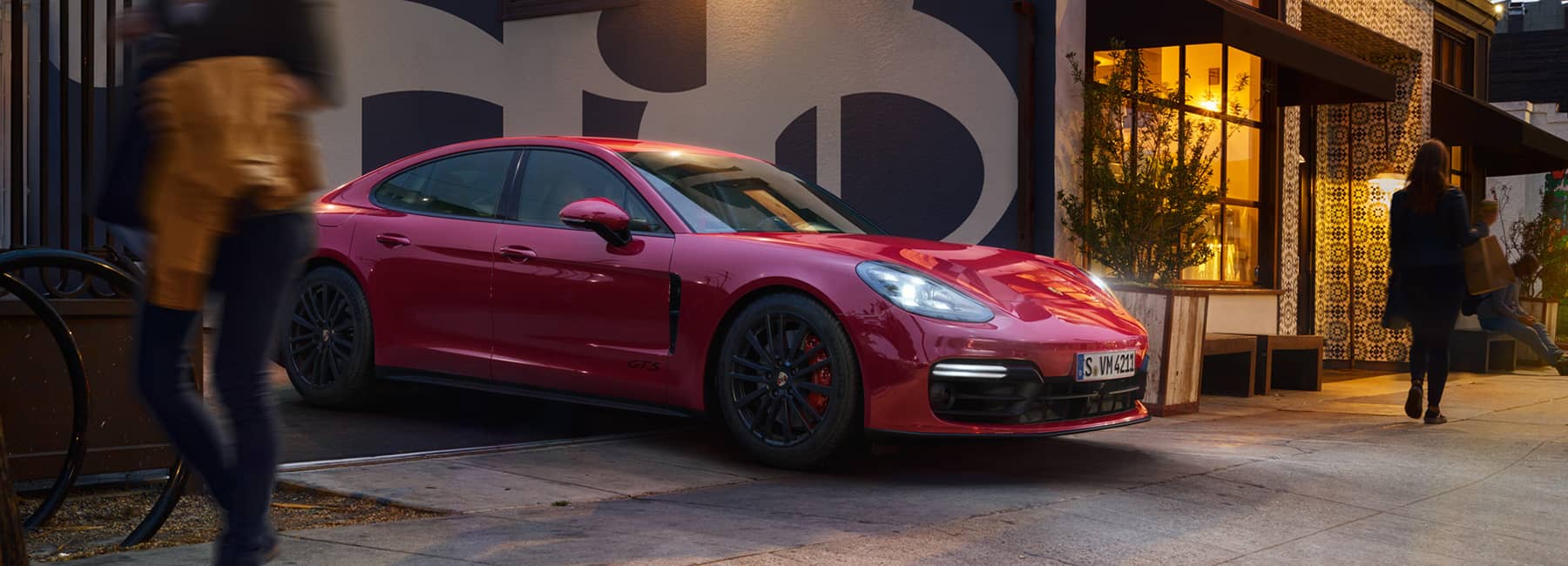 A red Porsche parked outside a quaint store.