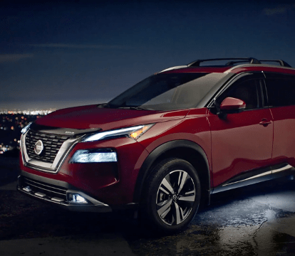 Front half of a red 2022 Nissan Rogue in front of a city skyline